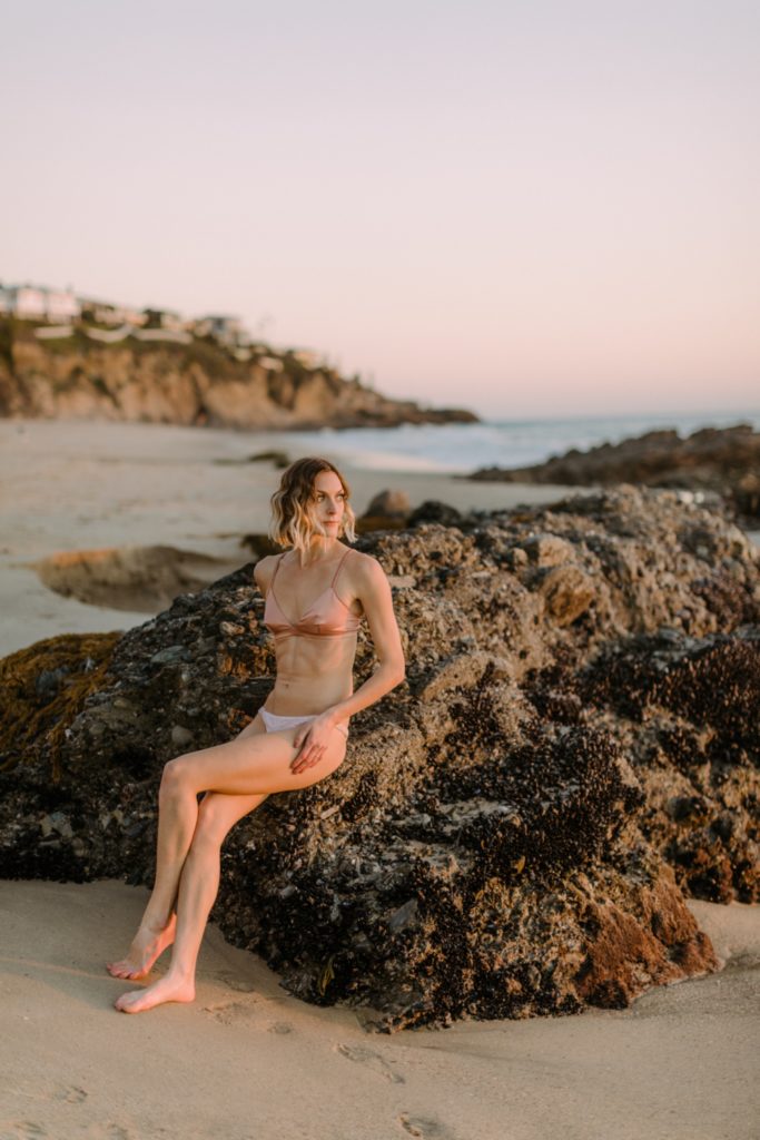 girl posing on rocks in sunset for laguna beach boudoir session