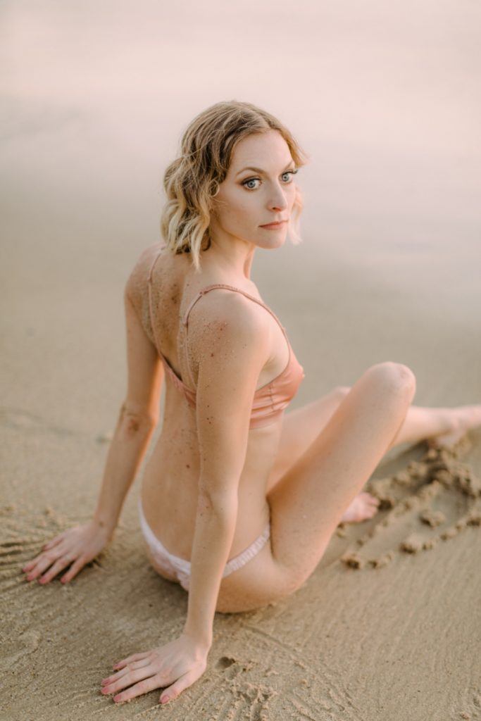 girl sitting on beach covered in sand for laguna beach boudoir session