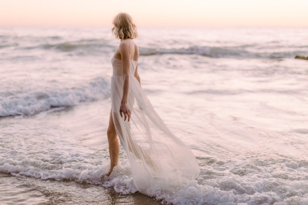 a girl running in the ocean for laguna beach boudoir session