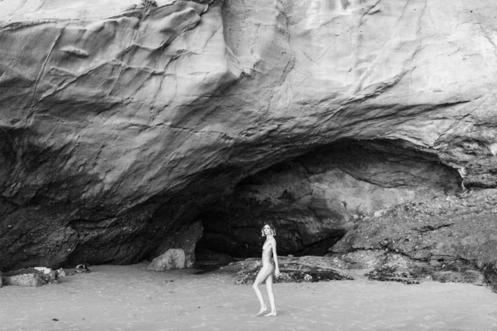 girl poses nude in front of beach cliffs for laguna beach boudoir session